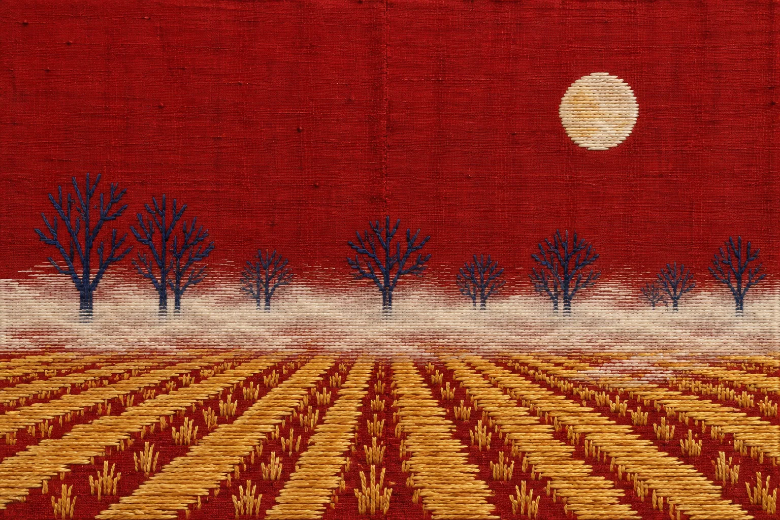 Phulkari embroidery of fog lying over gold-stitched fields and bare trees at night, under a full moon worked in white-gold floss.